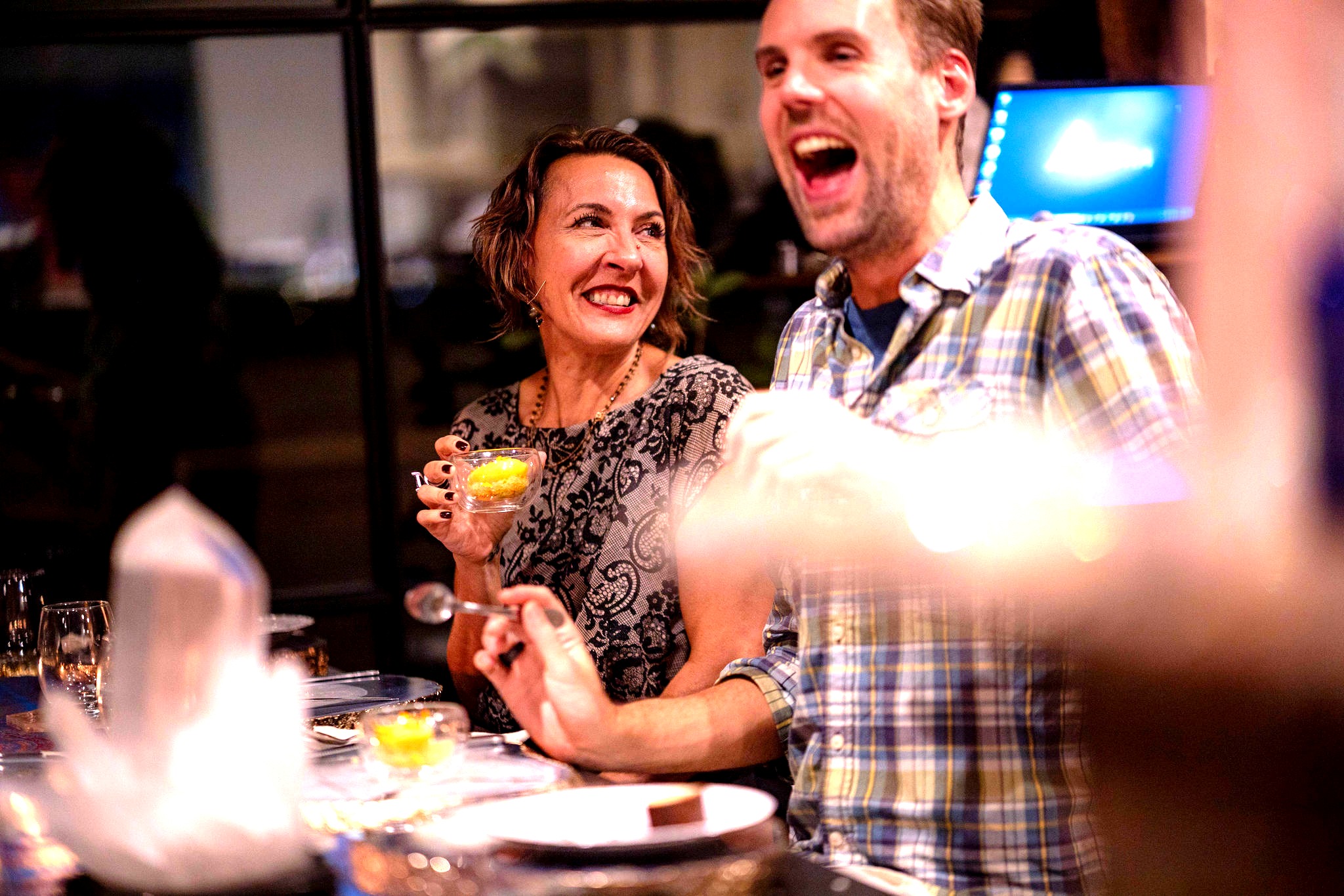 Guests laughing at the dinner table, warm candlelit atmosphere